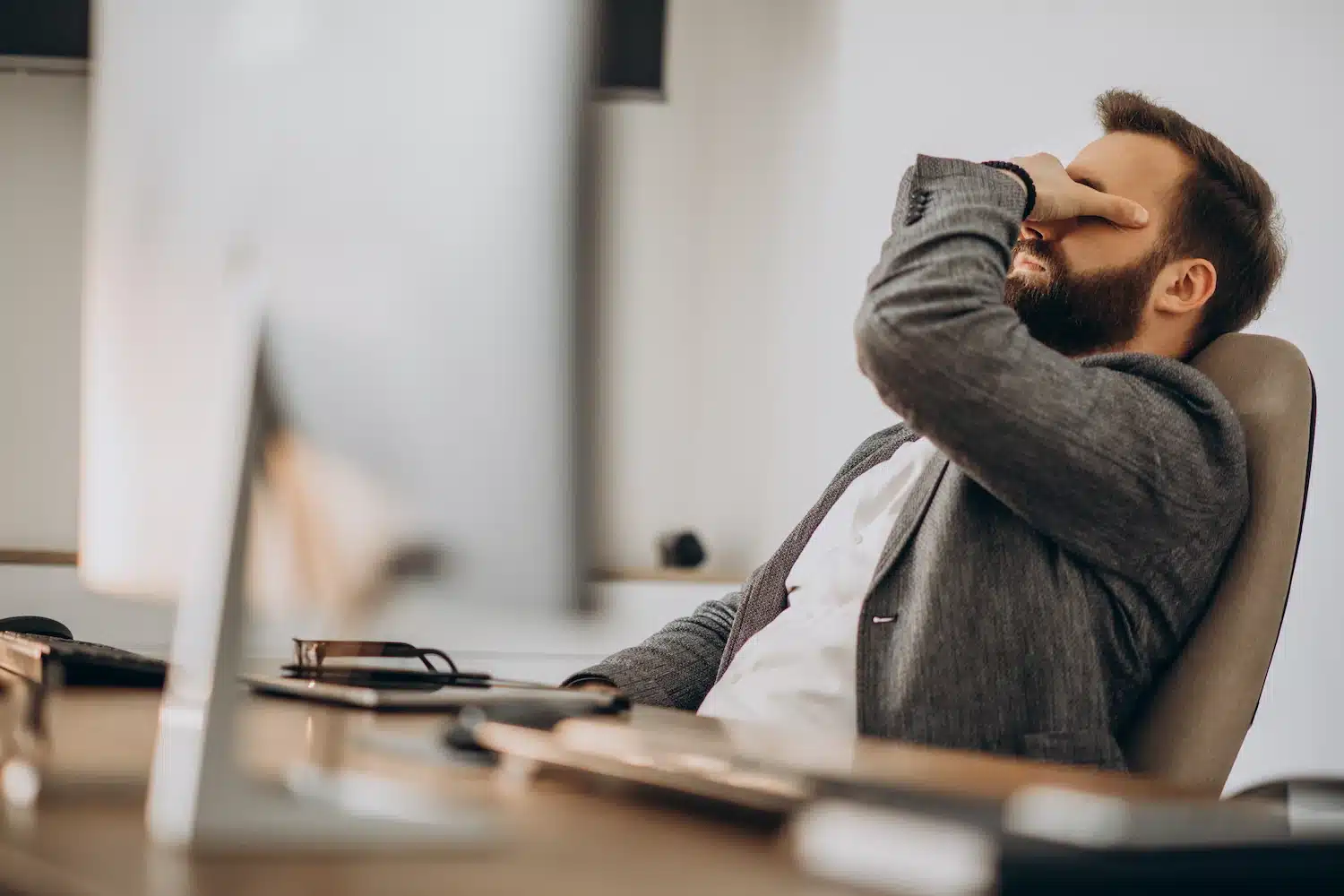 personne assise au bureau se frottant le visage, exprimant de la fatigue ou du stress au travail