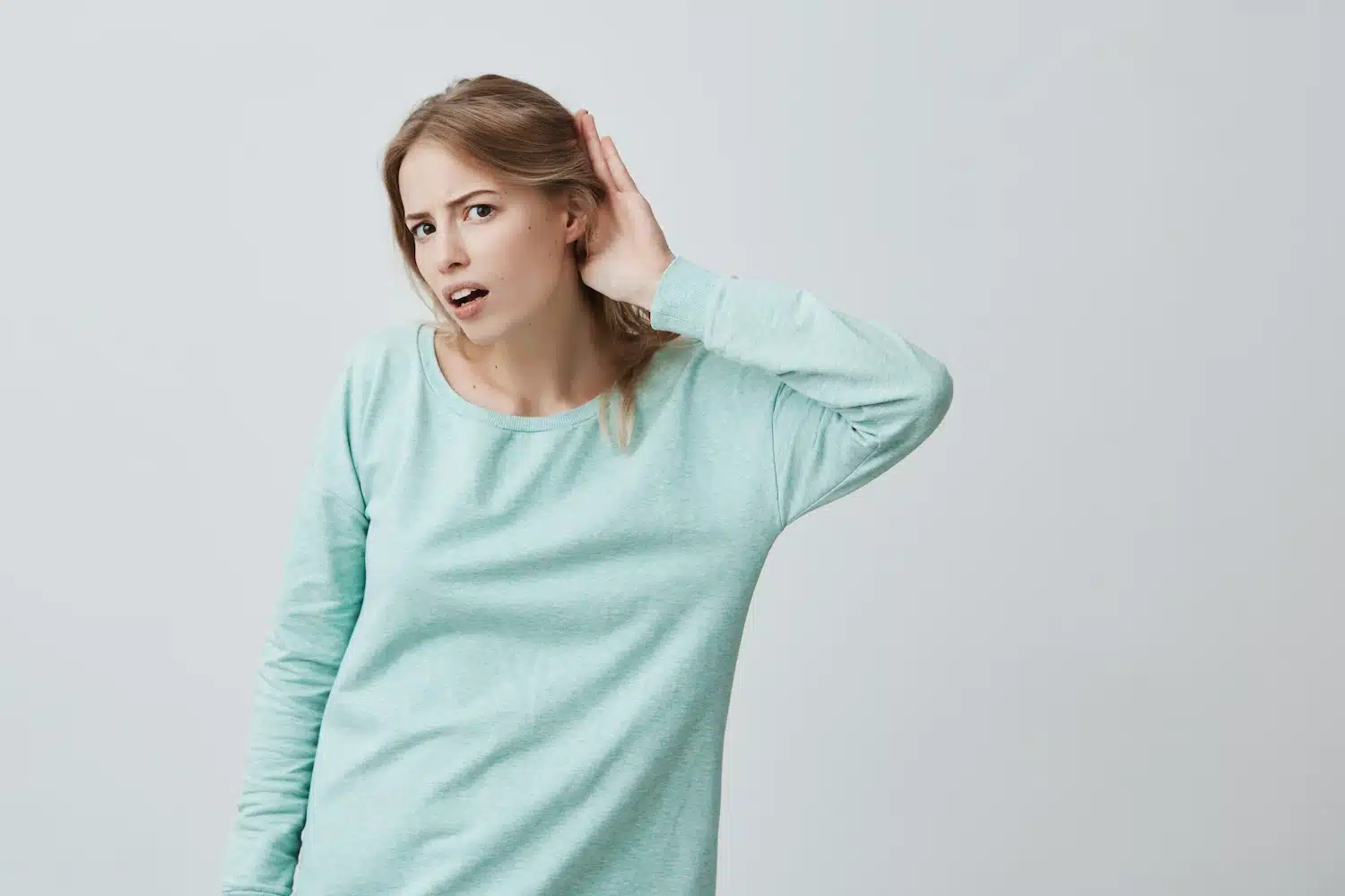 personne penchant la tête et plaçant une main derrière l’oreille pour mieux écouter